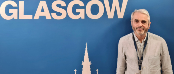 Professor Tom Evans stood in front of wall with the word Glasgow behind him