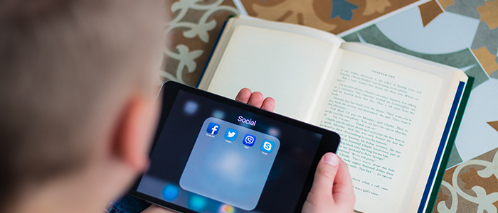 Boy holding a tablet and reading a book