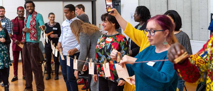 A group of people standing behind a line of string with cards pegged onto it
