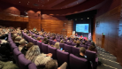 A photo from the back of a busy lecture room with Nicola and Kez presenting at the front