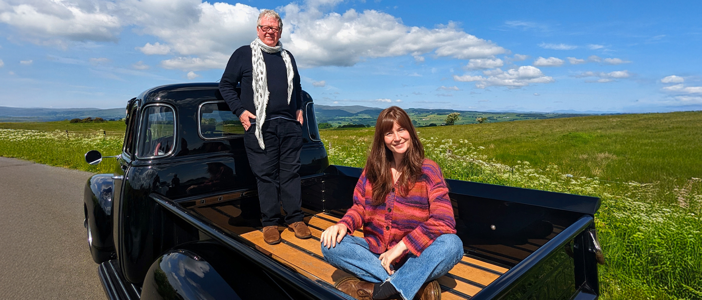 Natasha Raskin-Sharp and Phil Serrell on the back of a classic car (C) STV studios, BBC
