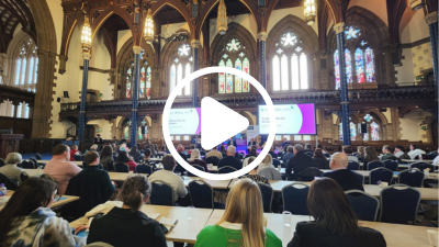 A photo of the Child Poverty and Public Debt Crisis conference with a 'play button' icon