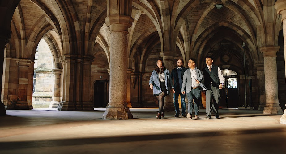 Dr Mark Wong (third from left) with colleagues Dr Mark Wong walking through the University of Glasgow's cloisters, talking to three colleagues who are walking alongside him