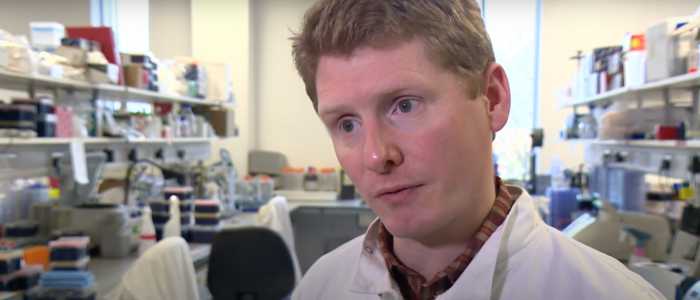 Screenshot from TV feature of Ed Hutchinson in a lab wearing a white lab coat.
