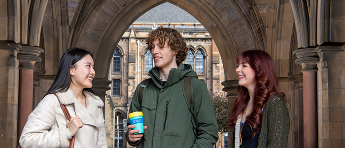 three students talking under at the west entrance of the Gilbert Scott building