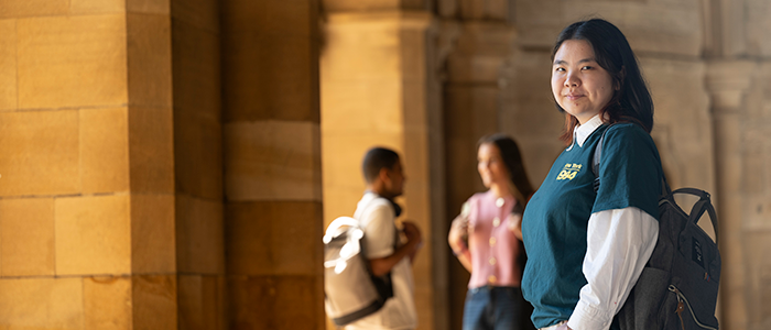 student looking to camera in cloisters with students in the background
