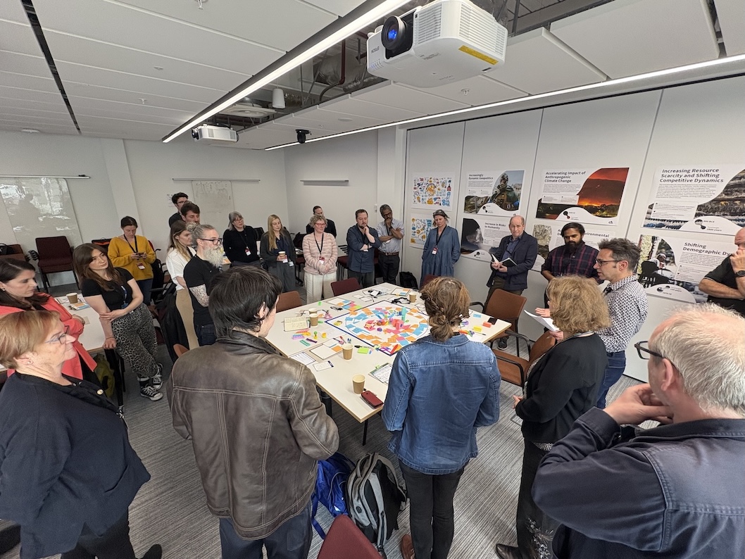 A group of people around a table with various objected lied out on it
