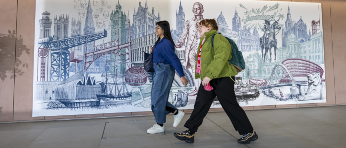 Students walking in front of mural in the Interior of the Adam Smith Building.