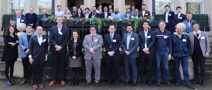 Group photo of attendees of the JEOL International CryoARM meeting on steps outside a stone building
