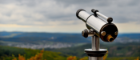 A telescope pointing to sky with landscape in background.