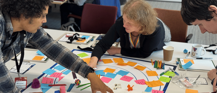 Two people leaning over a table covered with post-it notes and random items