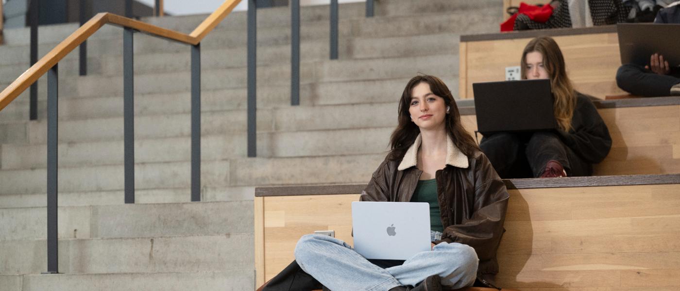 Students sitting in JMS on the step with laptops