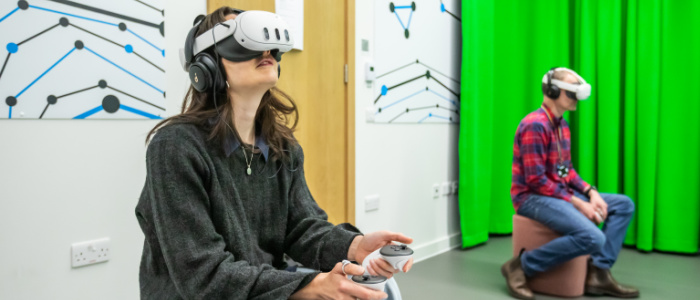 A user wears a headset and holds controls in both hands in the ARC-XR suite