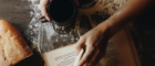 Table with someone holding book and a cup