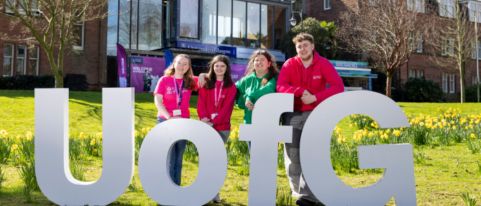 Students standing with letters that read 'UofG' outside Dumfries campus
