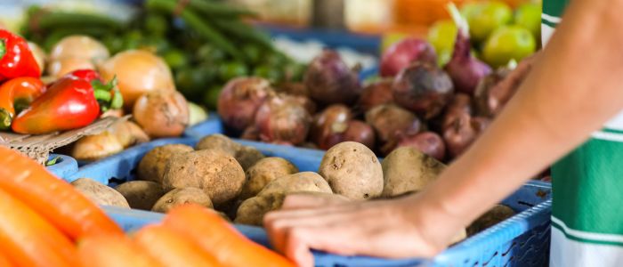 Vegetable food market stall with variety of different vegetables including potatoes, carrots and onions.
