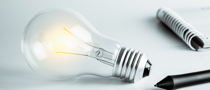 Lightbulb next to pen and paper