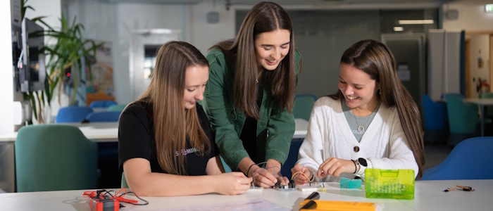 3 engineering students in class working on machinery