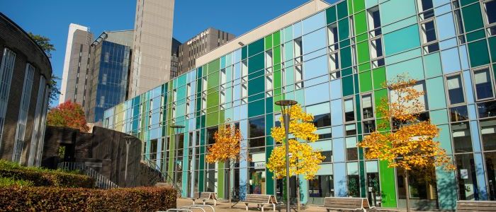 Outside view of the green and blue fraser building with autumn coloured trees in front