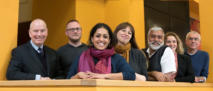 Group of people standing in a line on a yellow balcony