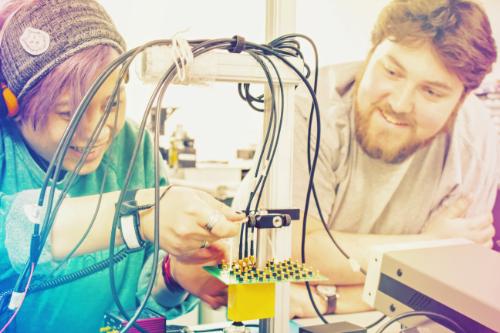 Two FUSE PhD students work on an experiment together in a research laboratory.
