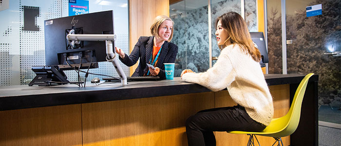 Staff and student chatting at welcome desk