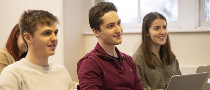 Students sitting in a lecture hall using their laptops