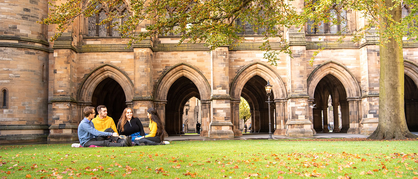 Students sitting on the grass beside the Cloisters