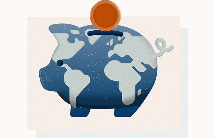 A piggy bank with a coin put into with the piggy bank having the world on it