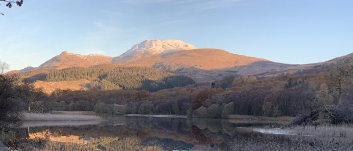 Loch Lomond with hills and trees in the background during sunset